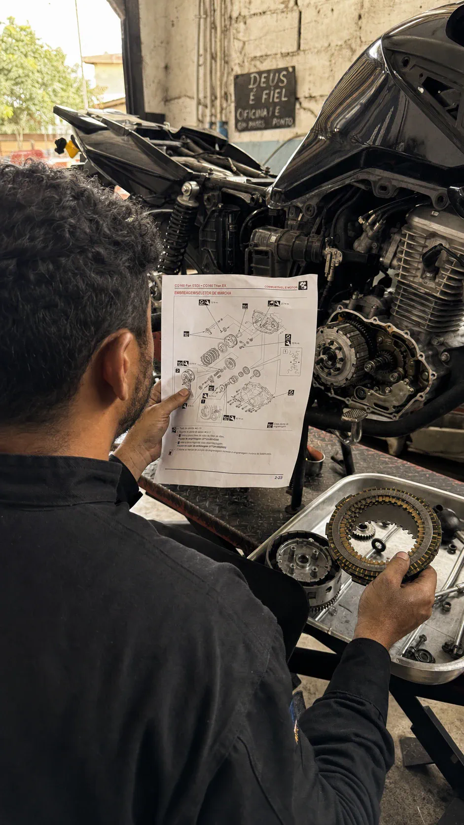 Mecânico consultando material visual durante manutenção de motocicleta
